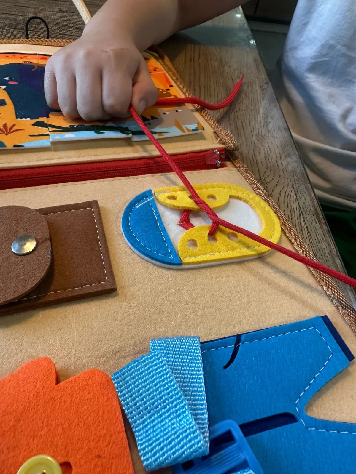 A child threading a colourful felt activity board